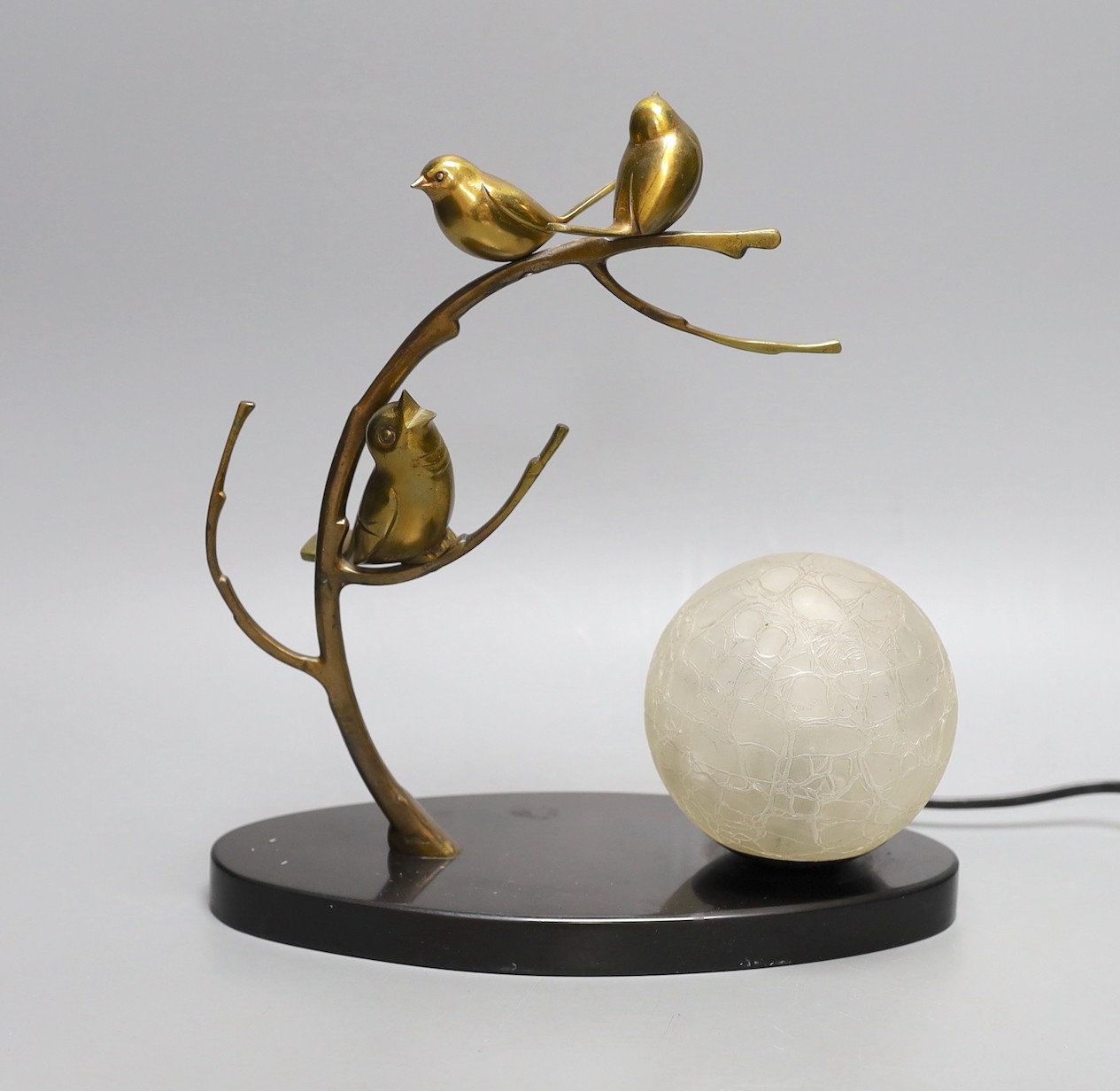 A French 1930's bronze lamp of stylistic birds in a tree, with a frosted globe shade on a black marble base, 27 cms high